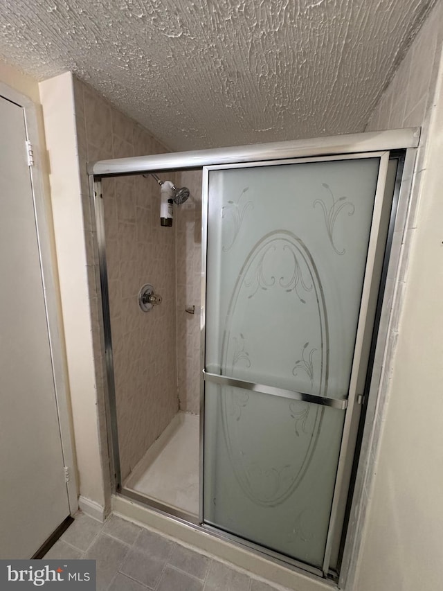 bathroom with a textured ceiling and a shower with shower door