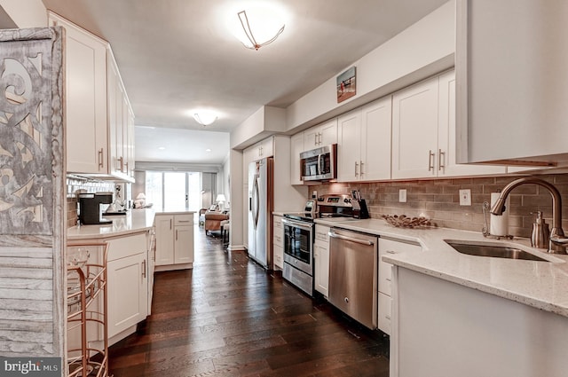 kitchen featuring white cabinetry, stainless steel appliances, decorative backsplash, sink, and light stone counters