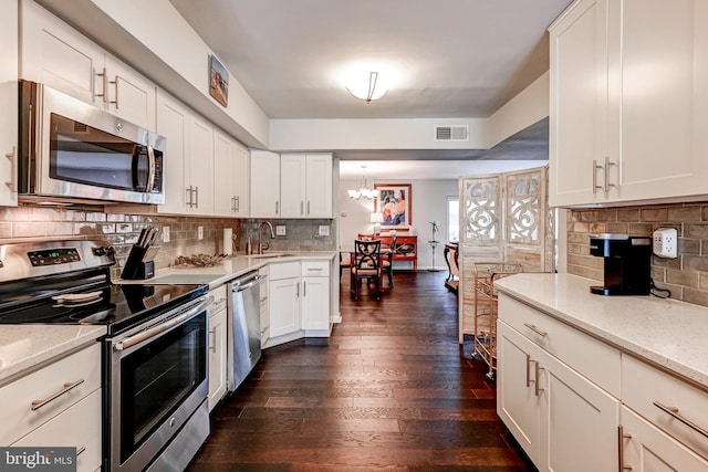 kitchen featuring appliances with stainless steel finishes, dark wood-type flooring, white cabinets, light stone counters, and sink