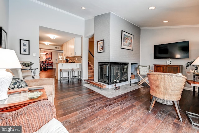 living room featuring ornamental molding, a fireplace, and hardwood / wood-style flooring