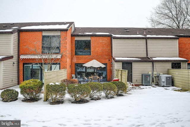 snow covered house featuring central AC unit