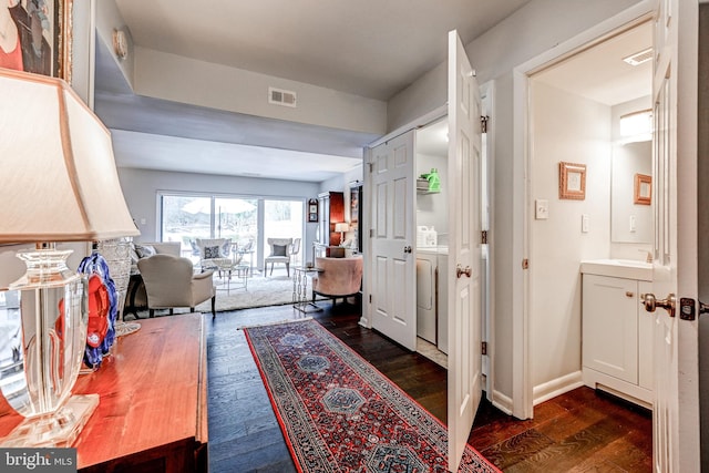 corridor with dark wood-type flooring and washing machine and clothes dryer