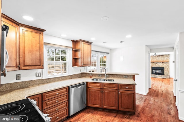 kitchen with a brick fireplace, appliances with stainless steel finishes, dark hardwood / wood-style floors, pendant lighting, and sink