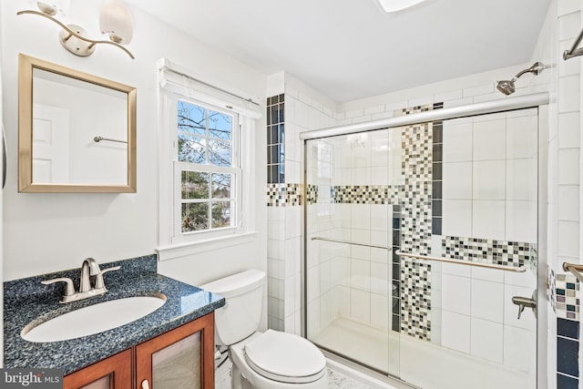 bathroom with toilet, vanity, and a shower with door