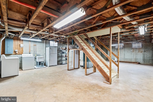 basement featuring white refrigerator, sink, washer and clothes dryer, and electric panel