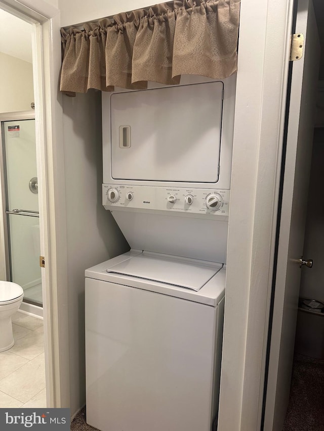 washroom with light tile patterned floors and stacked washing maching and dryer