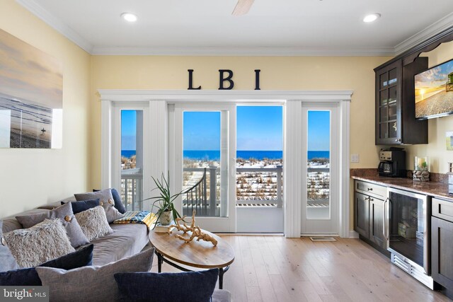 living room featuring crown molding, indoor bar, wine cooler, and light hardwood / wood-style floors