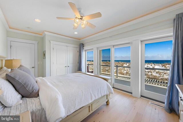 bedroom with a water view, light hardwood / wood-style flooring, ornamental molding, a closet, and access to exterior