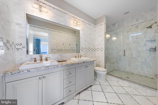 bathroom featuring tile walls, vanity, a shower with door, and toilet