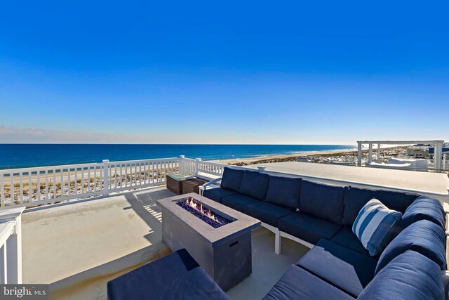 view of patio / terrace with a water view, an outdoor living space with a fire pit, and a view of the beach