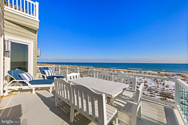 view of patio / terrace with a balcony, a water view, and a beach view