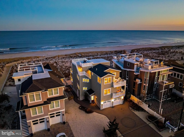 aerial view at dusk with a view of the beach and a water view