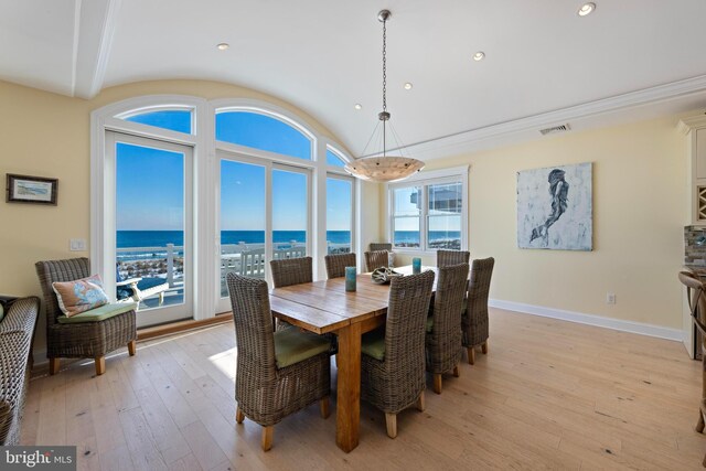 dining space with a water view, vaulted ceiling, and light hardwood / wood-style flooring