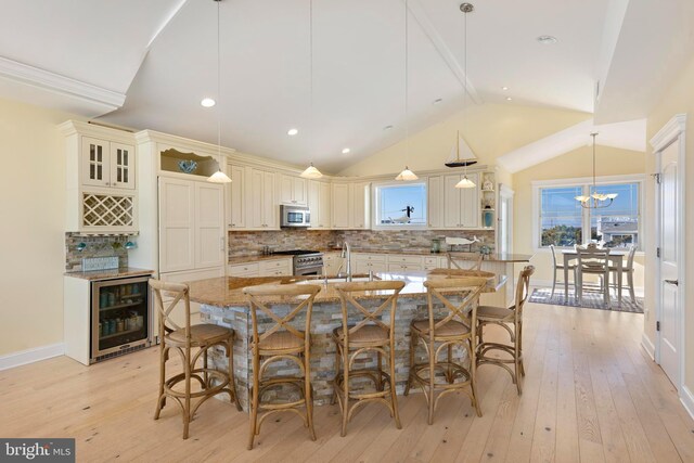 kitchen featuring pendant lighting, stainless steel appliances, a large island, and light stone countertops