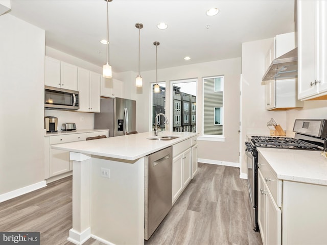 kitchen featuring white cabinetry, a center island with sink, appliances with stainless steel finishes, hanging light fixtures, and sink