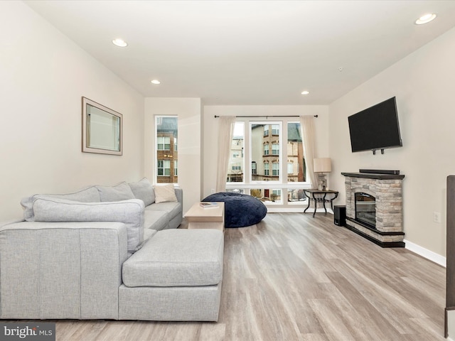 living room with wood-type flooring and a stone fireplace