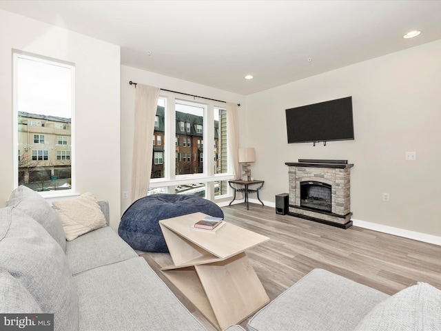 living room featuring light wood-type flooring and a stone fireplace