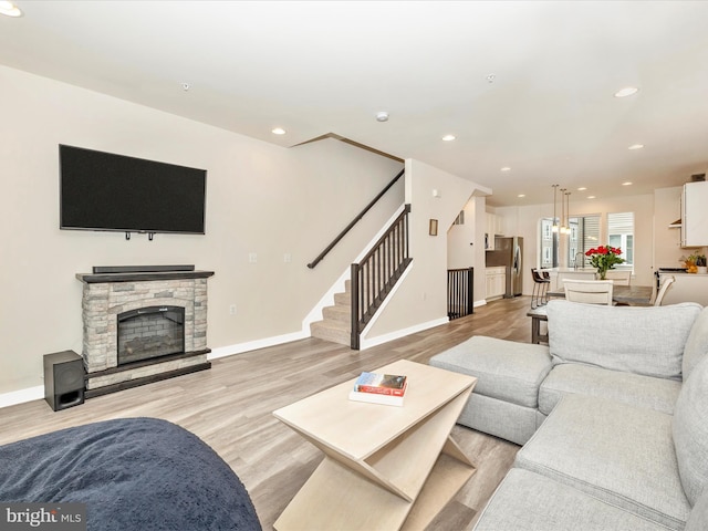 living room with light hardwood / wood-style floors and a stone fireplace