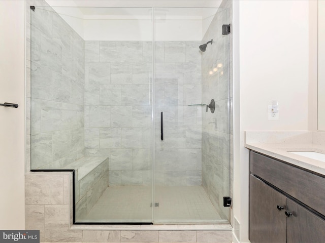 bathroom with a shower with shower door and vanity