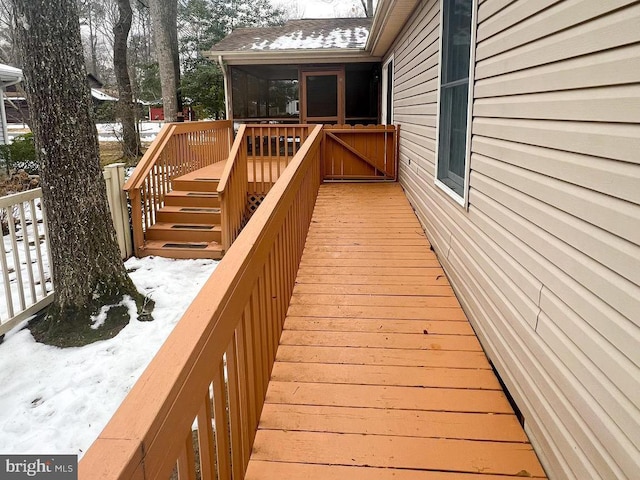 snow covered deck featuring a sunroom