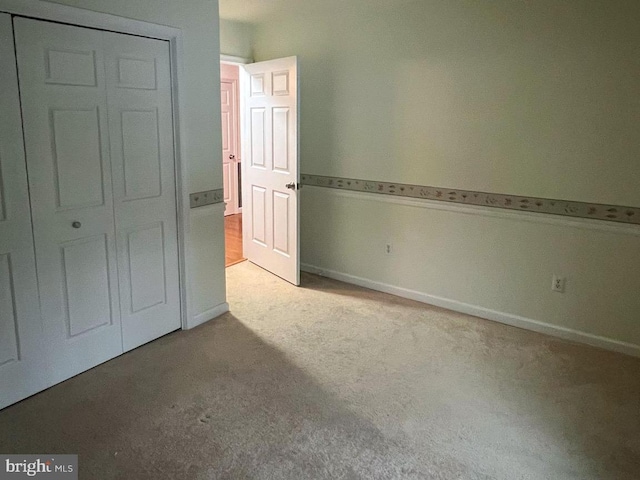 unfurnished bedroom with light carpet and a closet