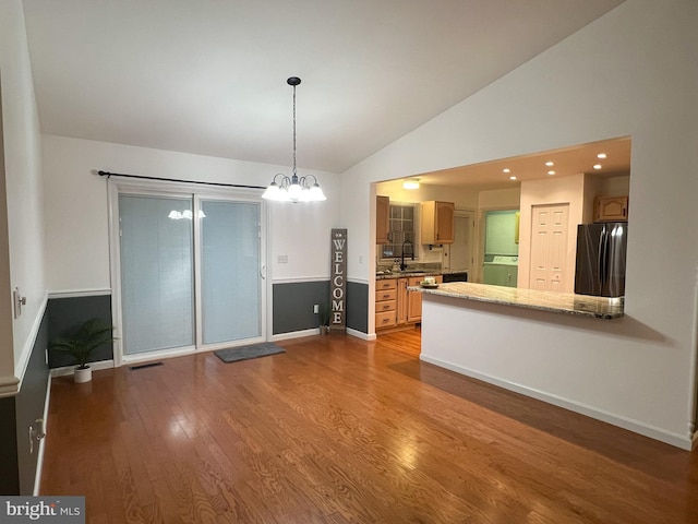 interior space with fridge, vaulted ceiling, light hardwood / wood-style flooring, washer / clothes dryer, and sink