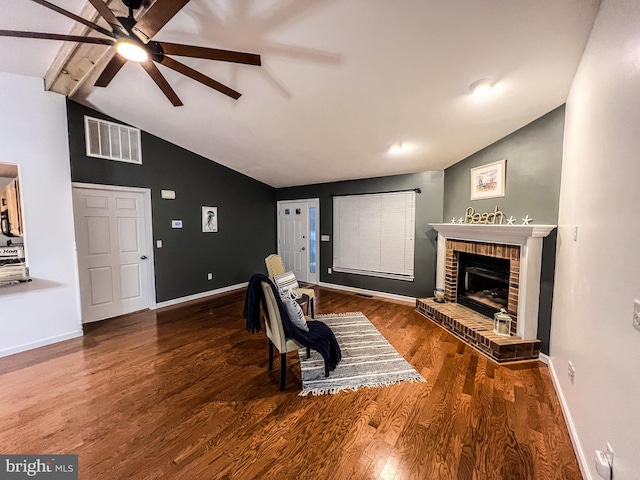 living room with ceiling fan, lofted ceiling with beams, a brick fireplace, and hardwood / wood-style flooring