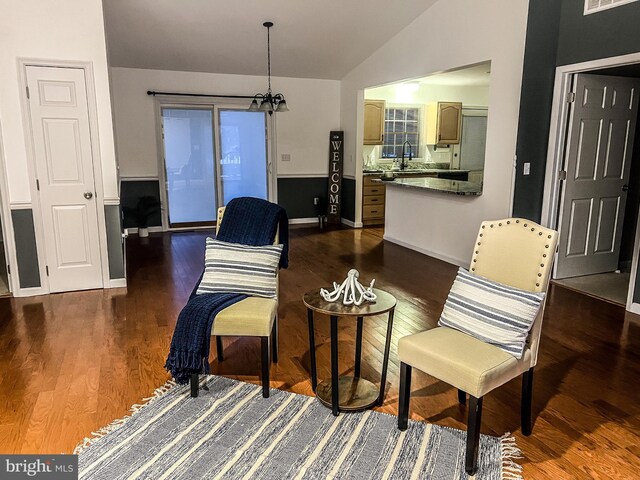 living area featuring dark hardwood / wood-style flooring, lofted ceiling, a chandelier, and sink