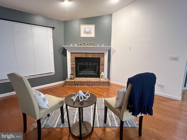 sitting room featuring vaulted ceiling, a fireplace, and wood-type flooring