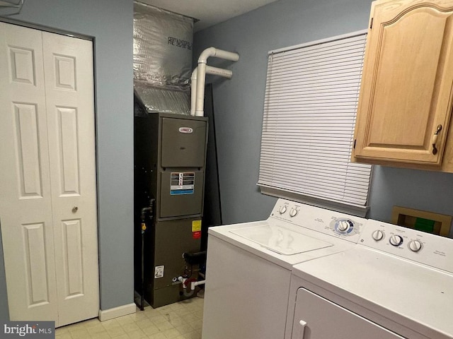 clothes washing area featuring cabinets and washer and clothes dryer