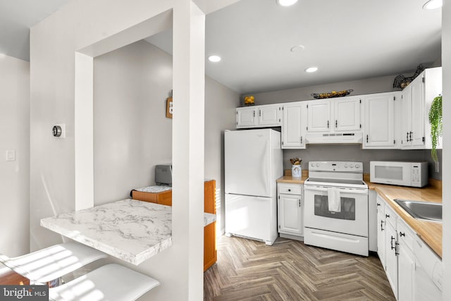 kitchen with sink, white appliances, white cabinets, and parquet floors