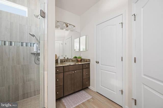 bathroom featuring vanity, wood-type flooring, and a shower with door