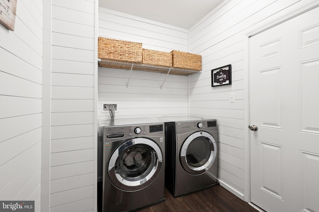 washroom with washing machine and dryer, dark hardwood / wood-style floors, and wood walls