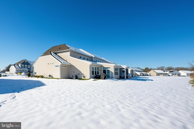 snow covered rear of property with cooling unit