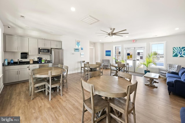 dining space featuring light hardwood / wood-style floors, ceiling fan, sink, and french doors