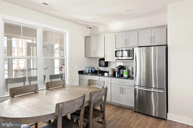 kitchen with appliances with stainless steel finishes, gray cabinetry, light hardwood / wood-style floors, and sink