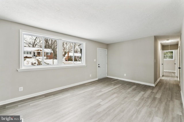 empty room with a textured ceiling and light hardwood / wood-style flooring