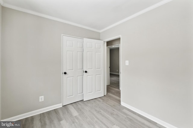 unfurnished bedroom with ornamental molding, a closet, and light wood-type flooring