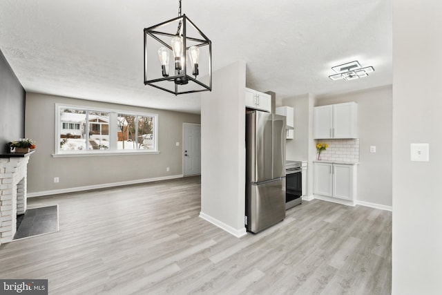 kitchen with pendant lighting, stainless steel appliances, a fireplace, decorative backsplash, and white cabinets