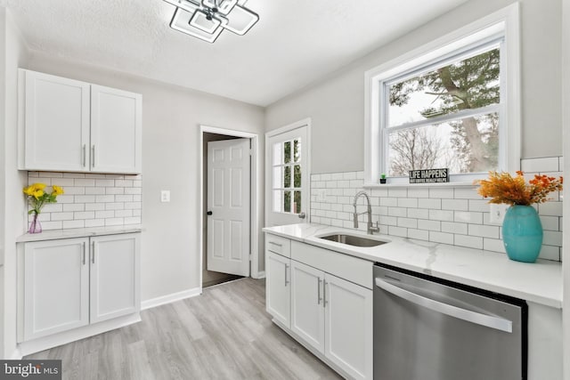 kitchen featuring sink, white cabinetry, backsplash, light stone countertops, and stainless steel dishwasher