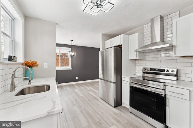 kitchen featuring white cabinetry, wall chimney range hood, and stainless steel appliances