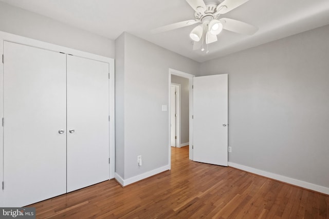 unfurnished bedroom featuring a ceiling fan, a closet, baseboards, and wood finished floors