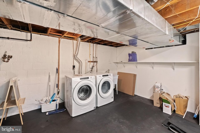 laundry area with laundry area, washing machine and dryer, and concrete block wall