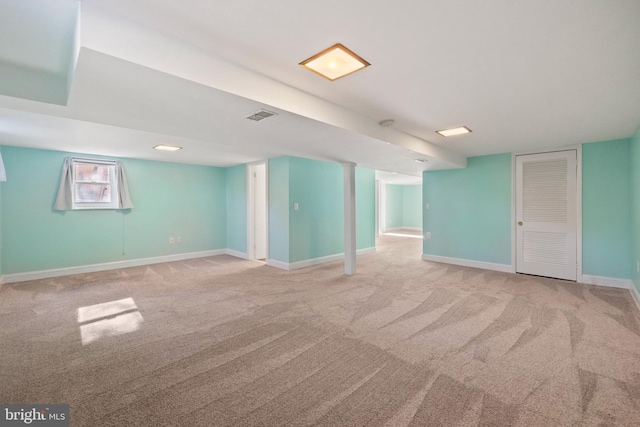 basement featuring visible vents, light carpet, and baseboards