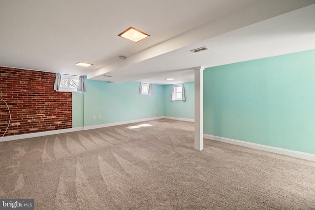 below grade area featuring brick wall, visible vents, baseboards, and carpet flooring