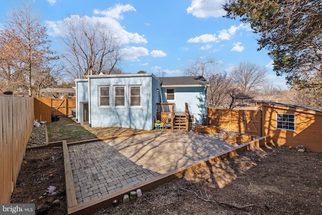 back of house featuring an outbuilding, a patio, a storage unit, and a fenced backyard