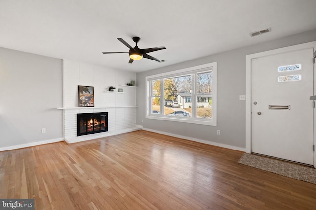 unfurnished living room with baseboards, a fireplace, visible vents, and wood finished floors