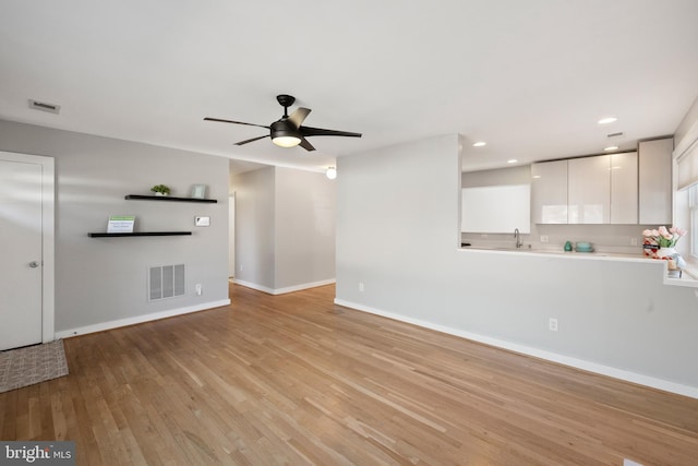 unfurnished living room with ceiling fan, light wood-style flooring, visible vents, and baseboards