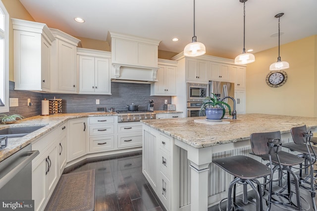 kitchen with a kitchen bar, stainless steel appliances, dark hardwood / wood-style floors, hanging light fixtures, and a kitchen island