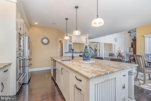 kitchen featuring sink, hanging light fixtures, a center island with sink, and dark hardwood / wood-style flooring